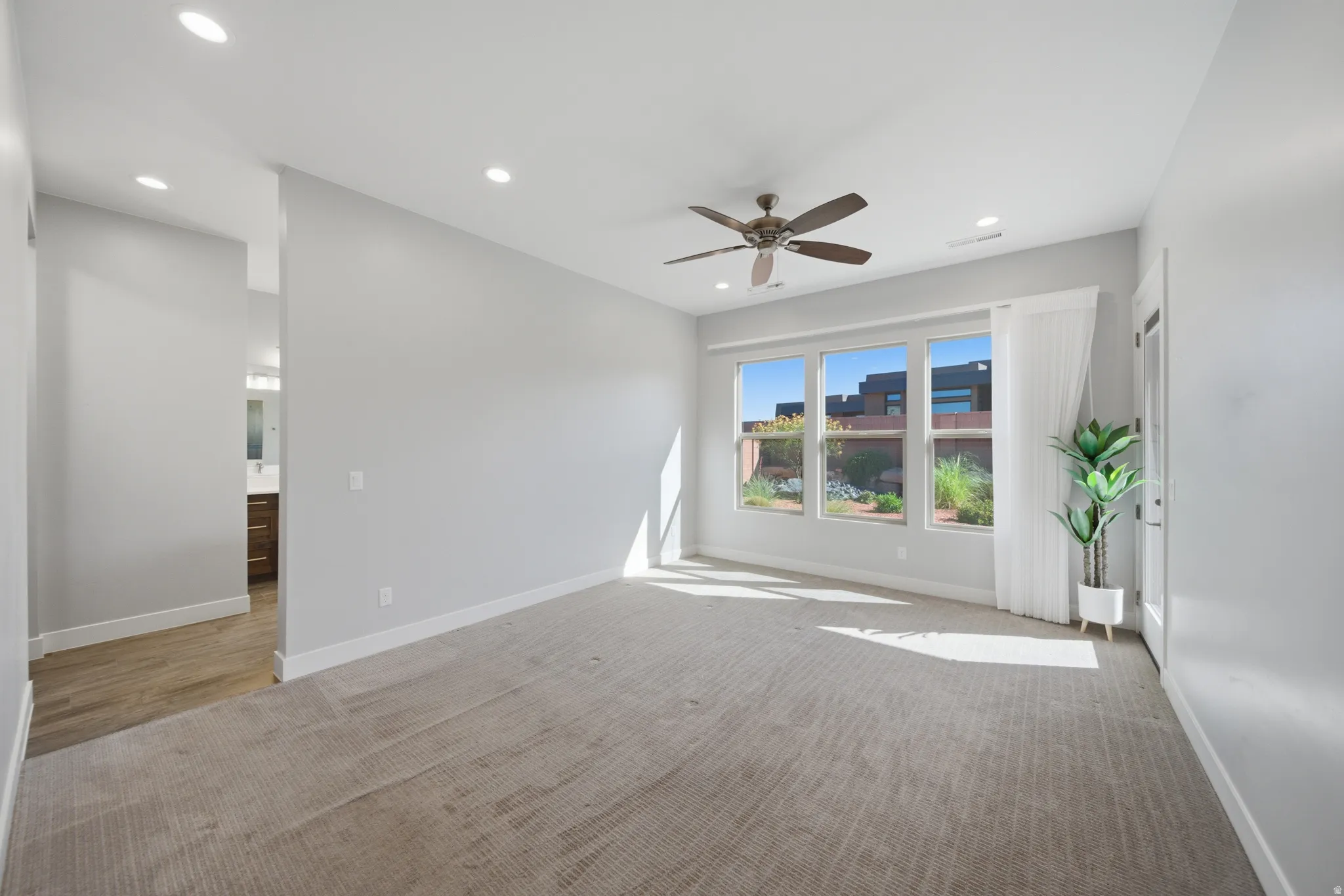Spacious room featuring light-colored carpeting, recessed lighting, and a ceiling fan