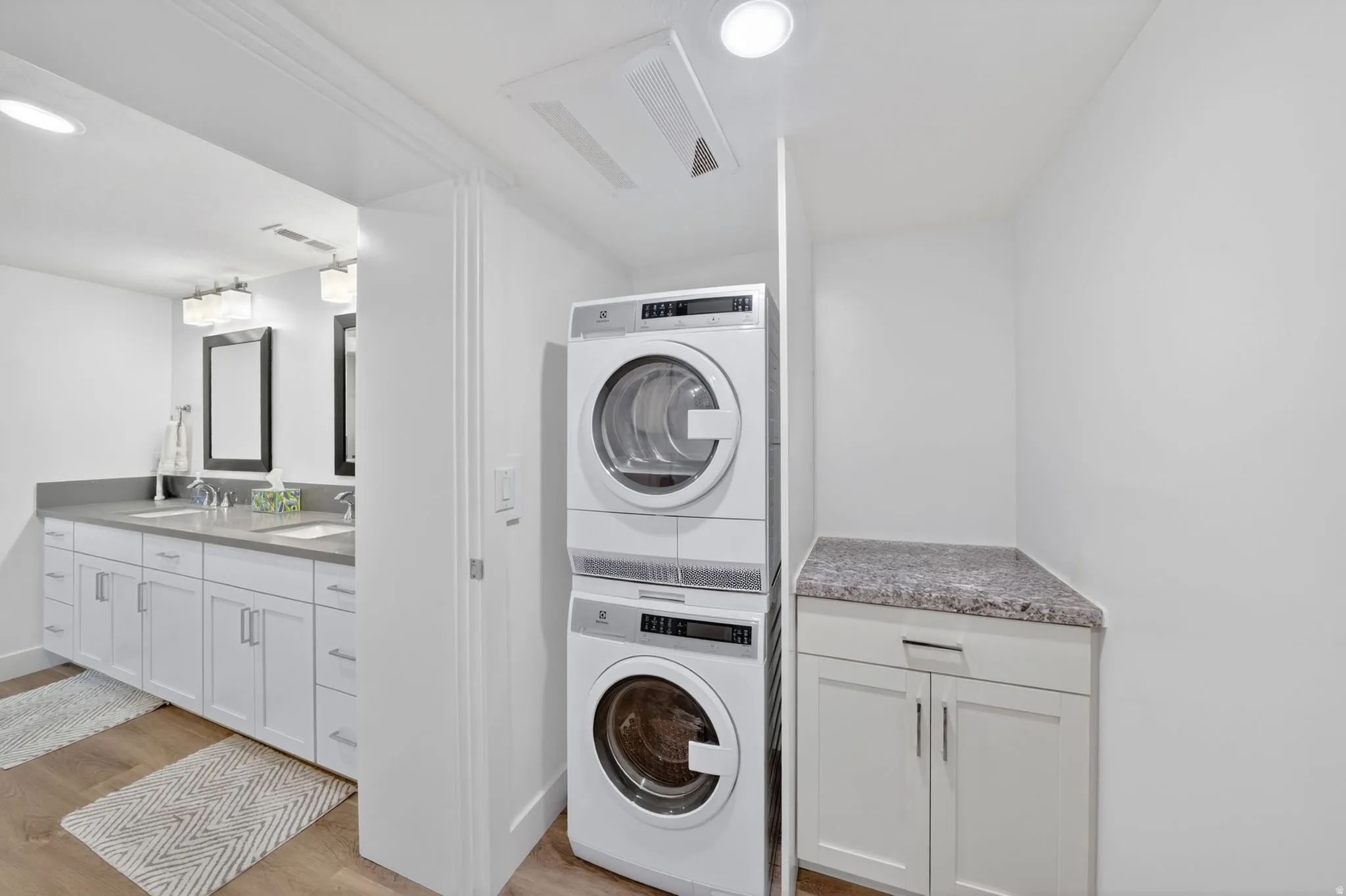 Mother in Law - Dedicated laundry area featuring a stacked washer and dryer, adjacent to a bathroom with a dual vanity, light gray countertop, and undermount sinks