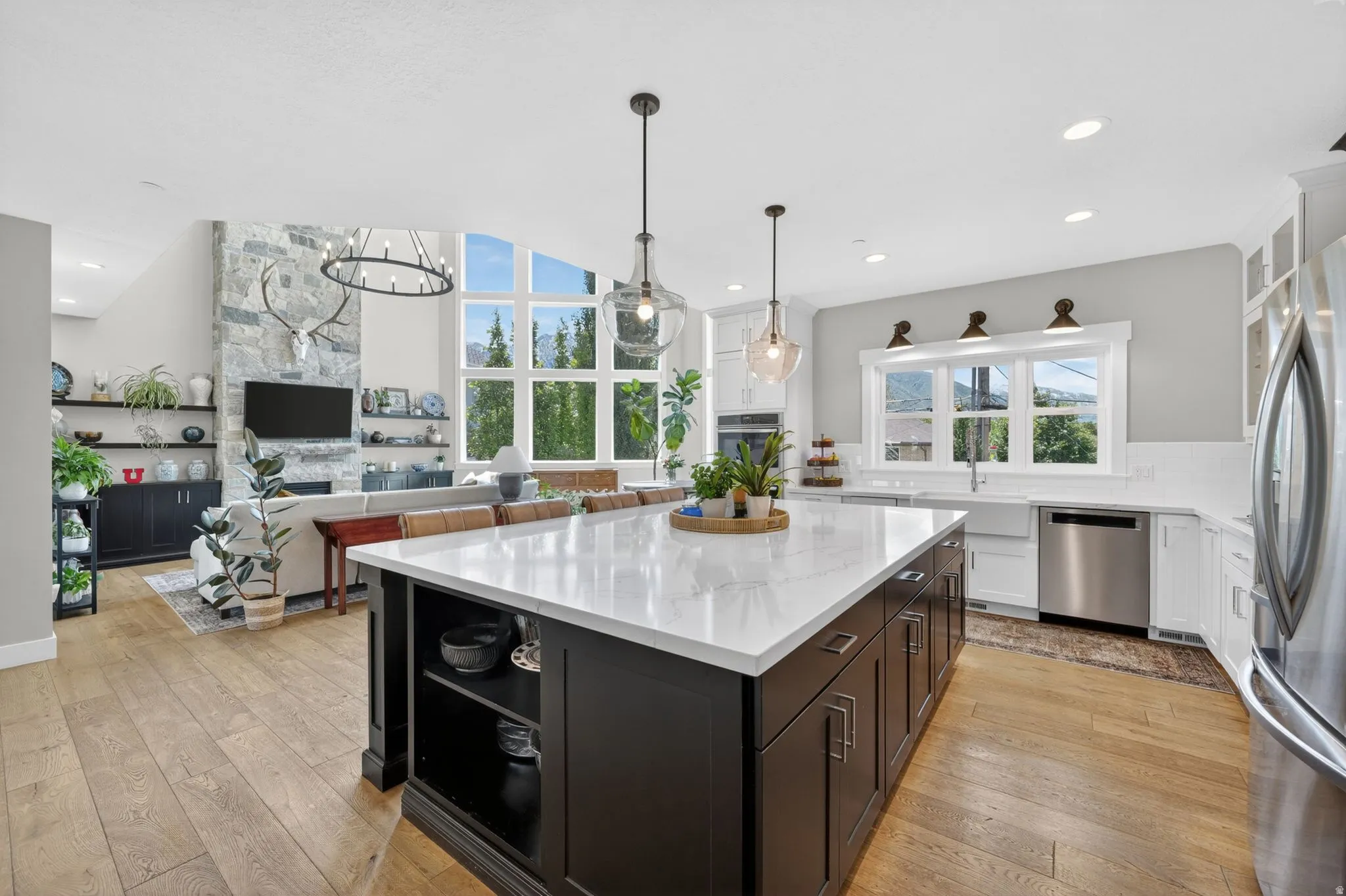 Open-concept kitchen featuring a large island with a light-toned countertop, dark cabinetry, and pendant lighting