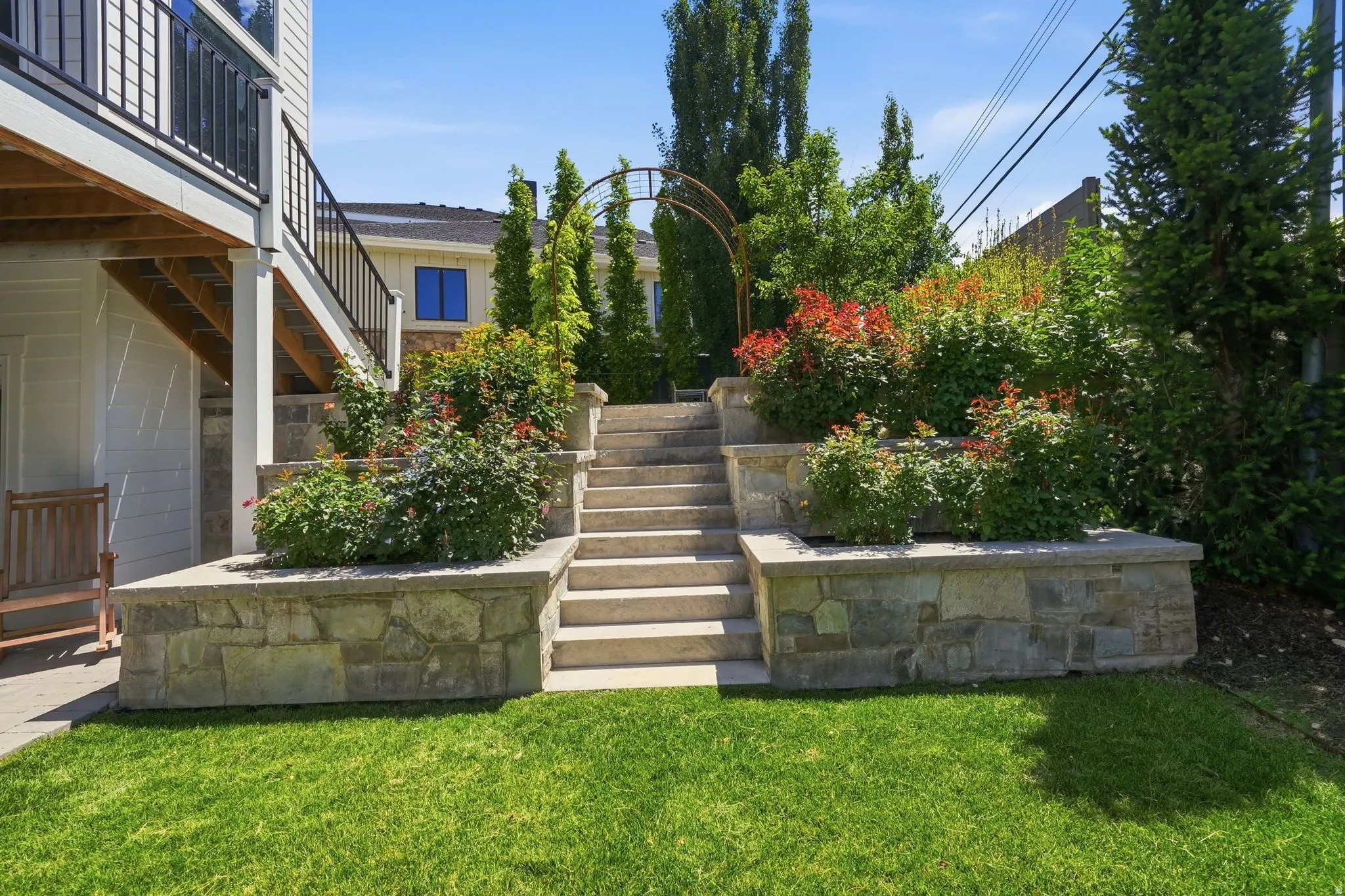 Tiered stone retaining walls define a landscaped backyard with a manicured lawn