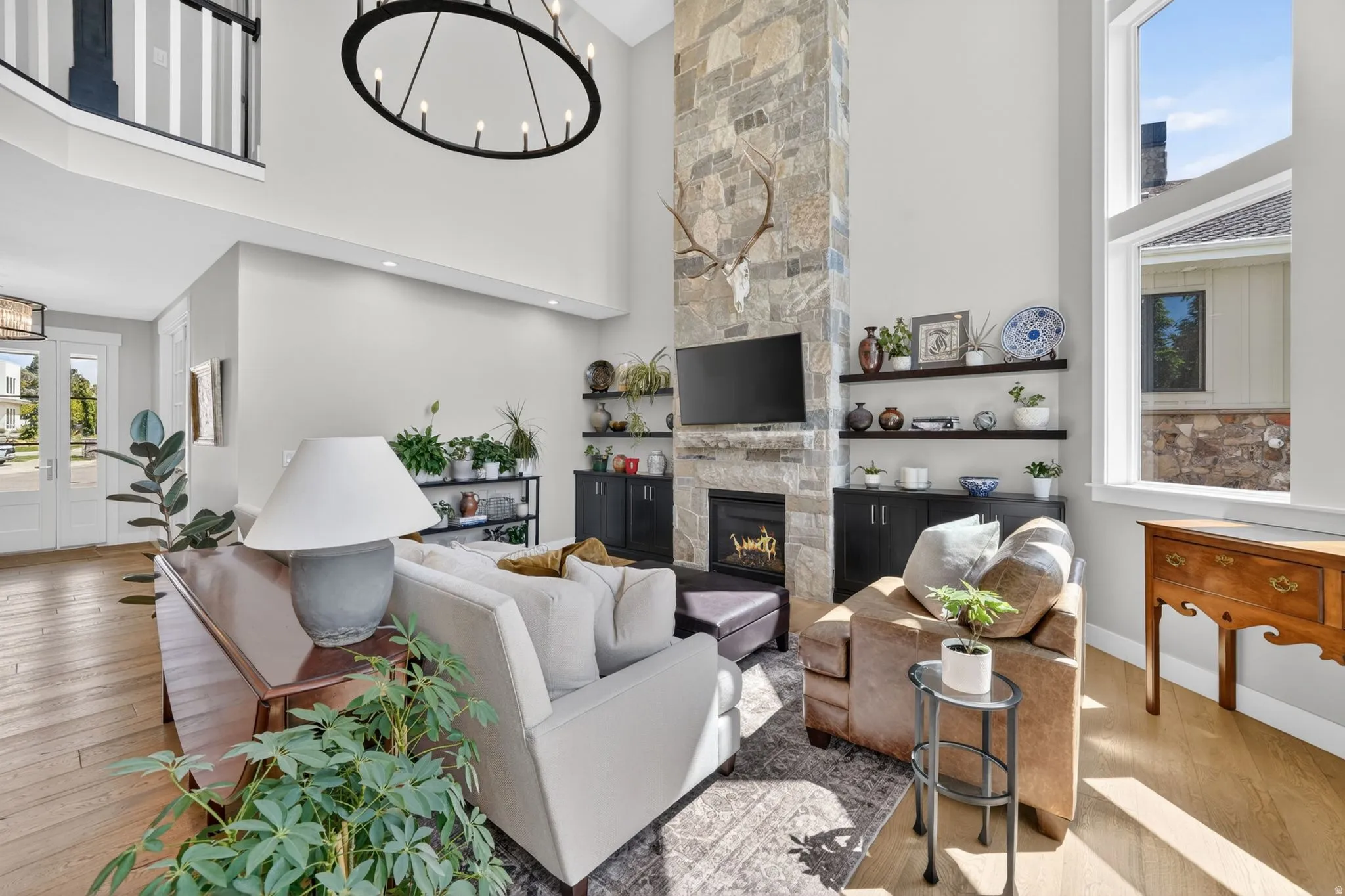 Great room featuring a soaring ceiling, stone-clad fireplace, and expansive windows