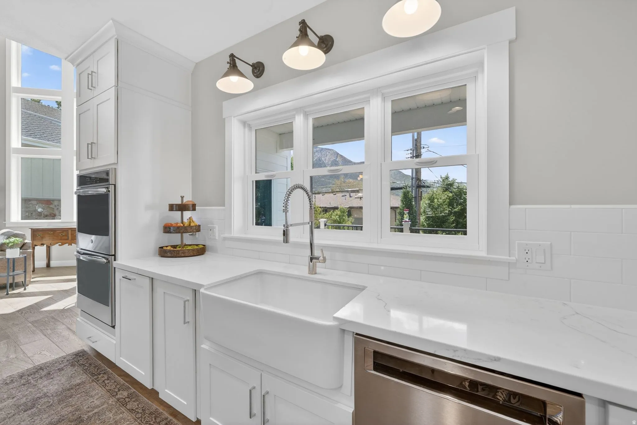 White kitchen featuring a farmhouse sink, stainless steel appliances, and solid surface countertops
