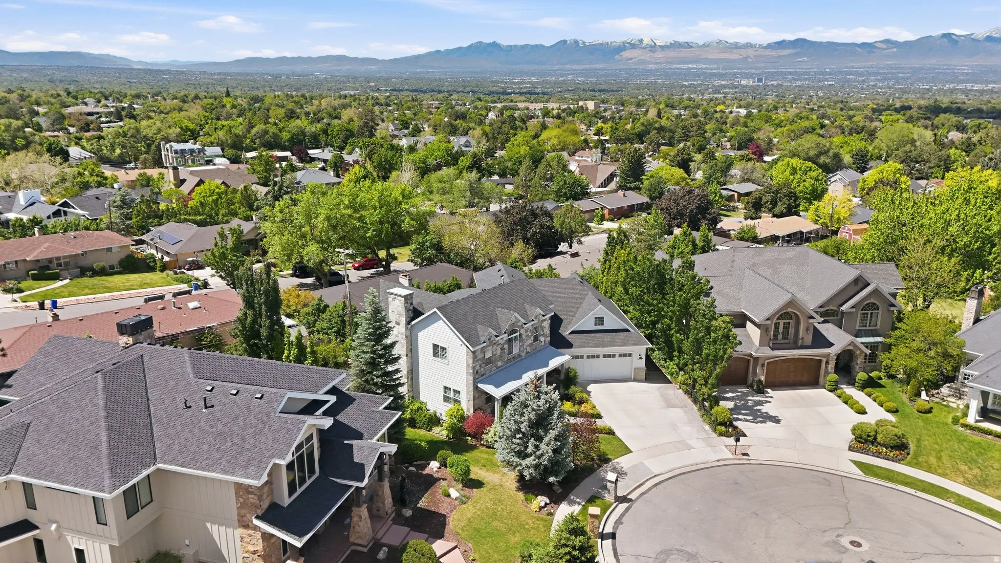 Residential neighborhood featuring a cul-de-sac, mature trees, and distant mountain ranges