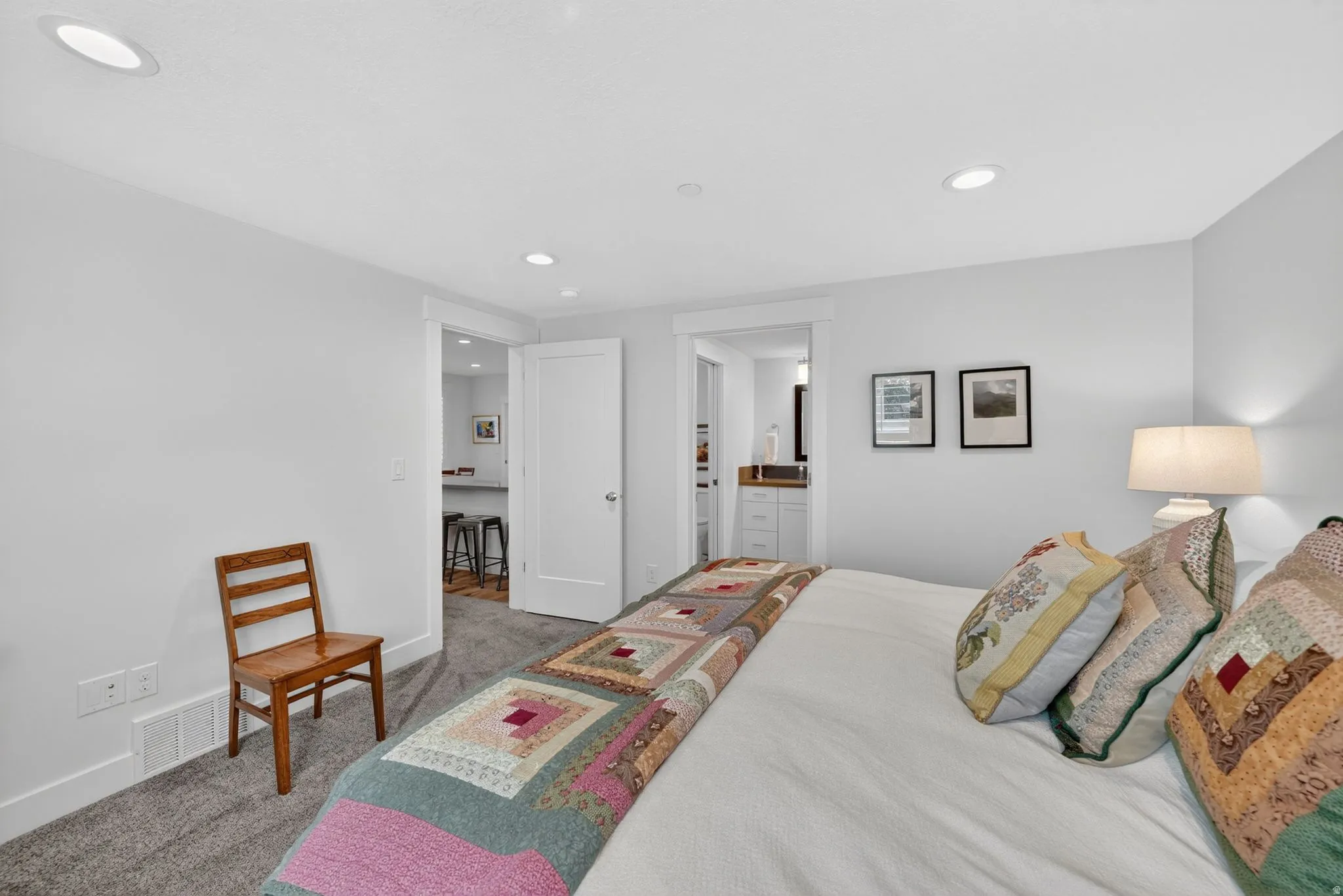 Recessed ceiling lighting illuminates a carpeted room featuring white walls and white trim