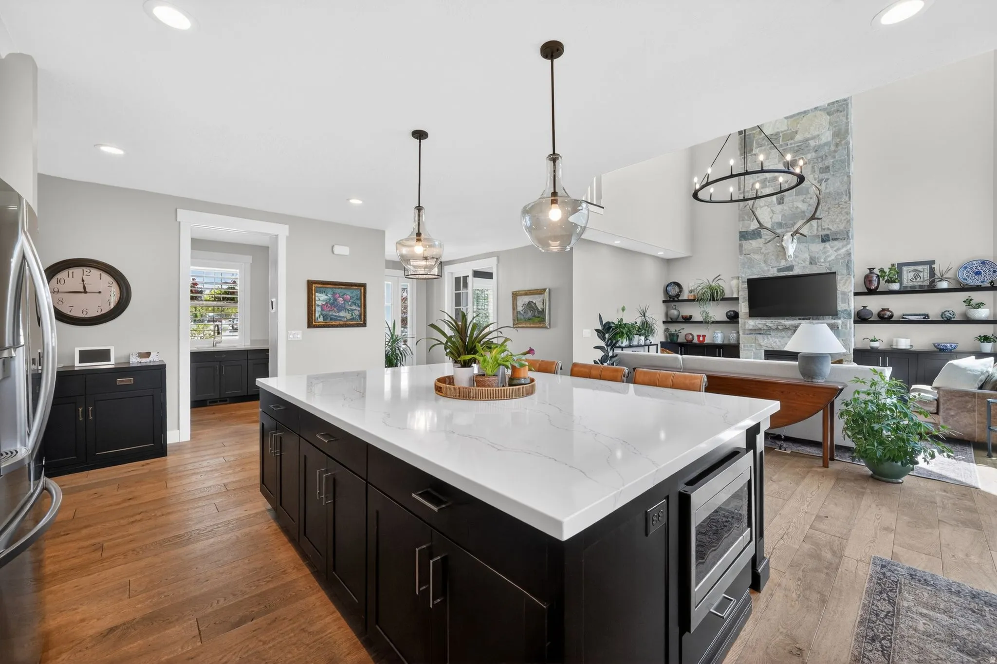 Open-concept kitchen featuring a large island with white stone countertop and under-counter microwave drawer