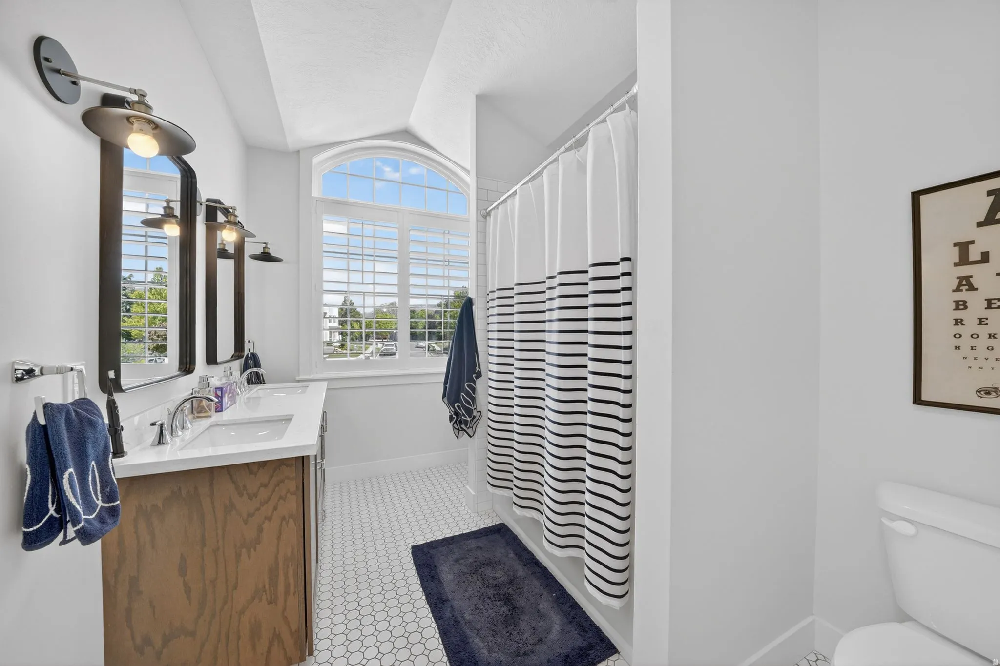 Bathroom featuring a wood-finish double vanity with white countertops, dual rectangular sinks, and wall-mounted lighting fixtures