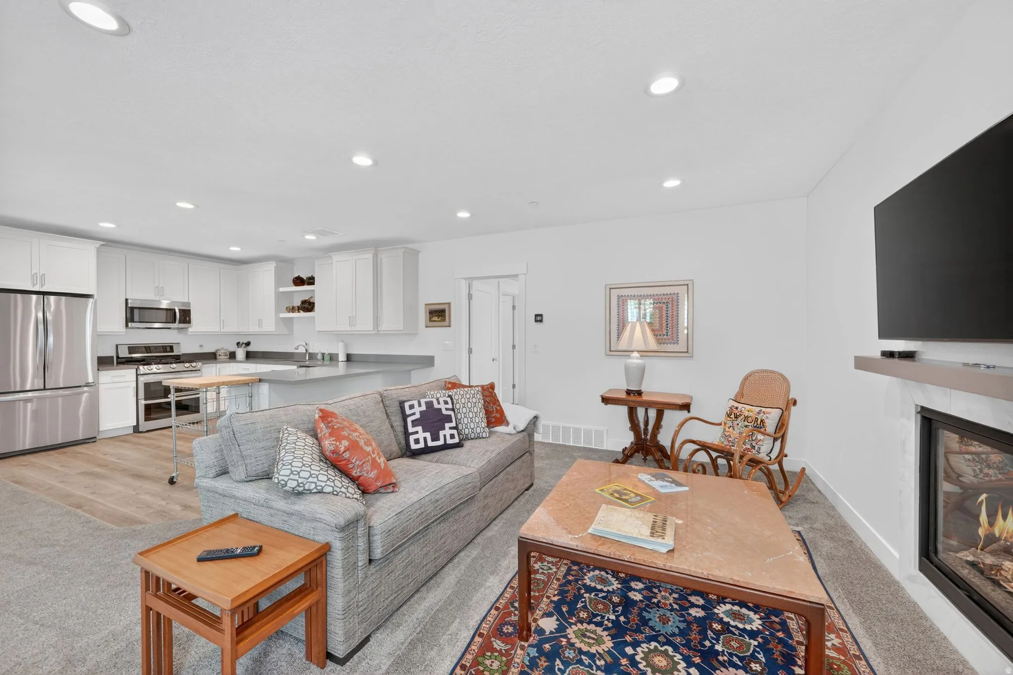 Mother in Law - Open-concept living space featuring a modern kitchen with stainless steel appliances, white cabinetry, and light-toned countertops