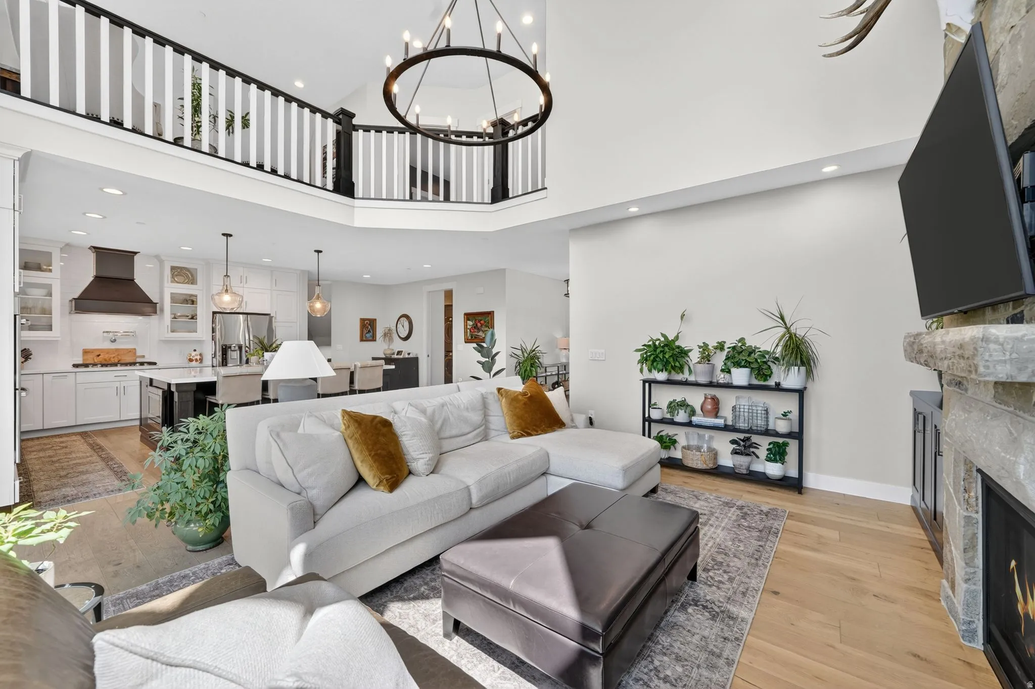 Vaulted living space featuring an open-concept layout, hardwood flooring, and a stone-clad fireplace