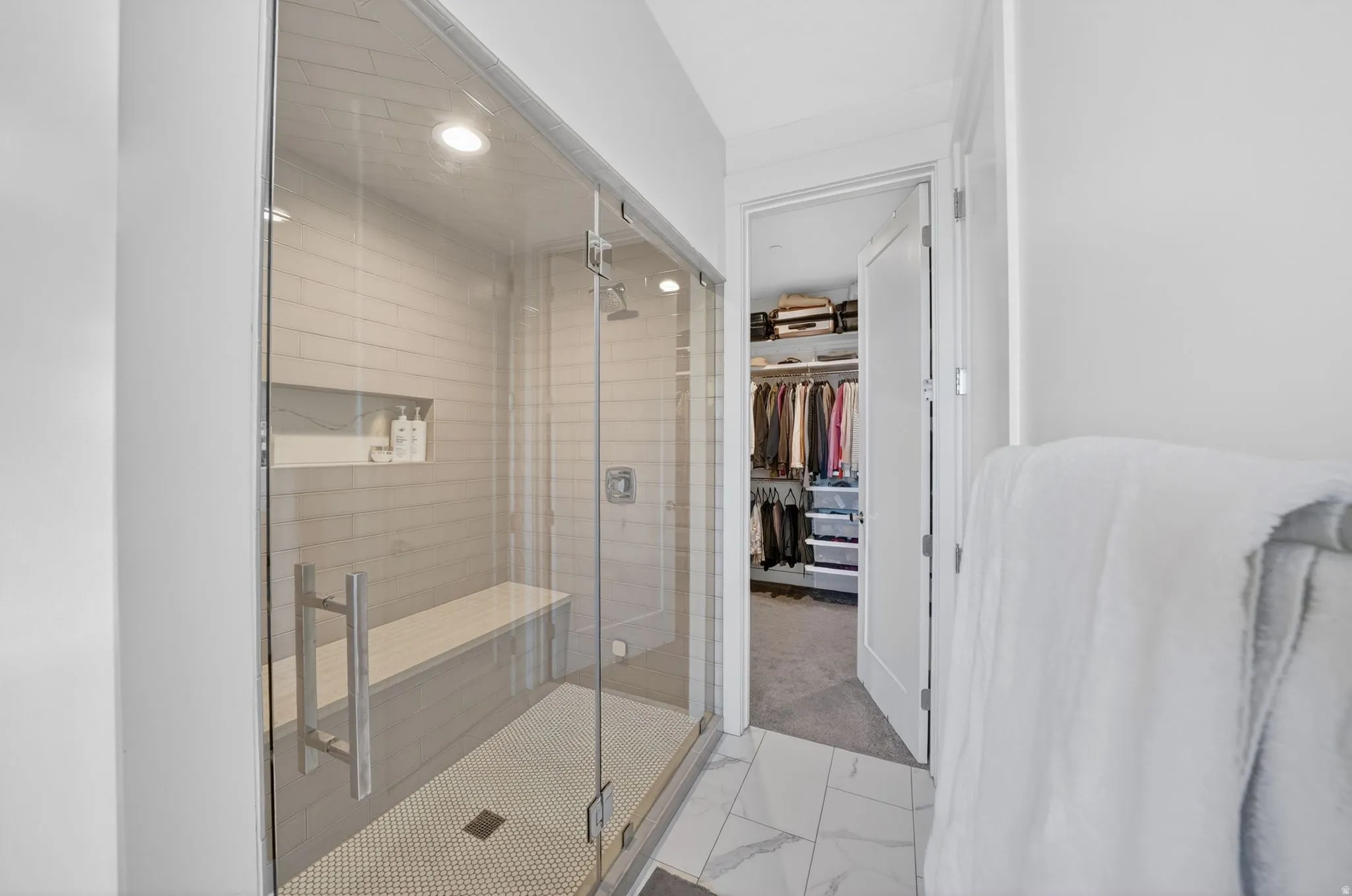 Glass-enclosed steam shower with a built-in bench and recessed shelving