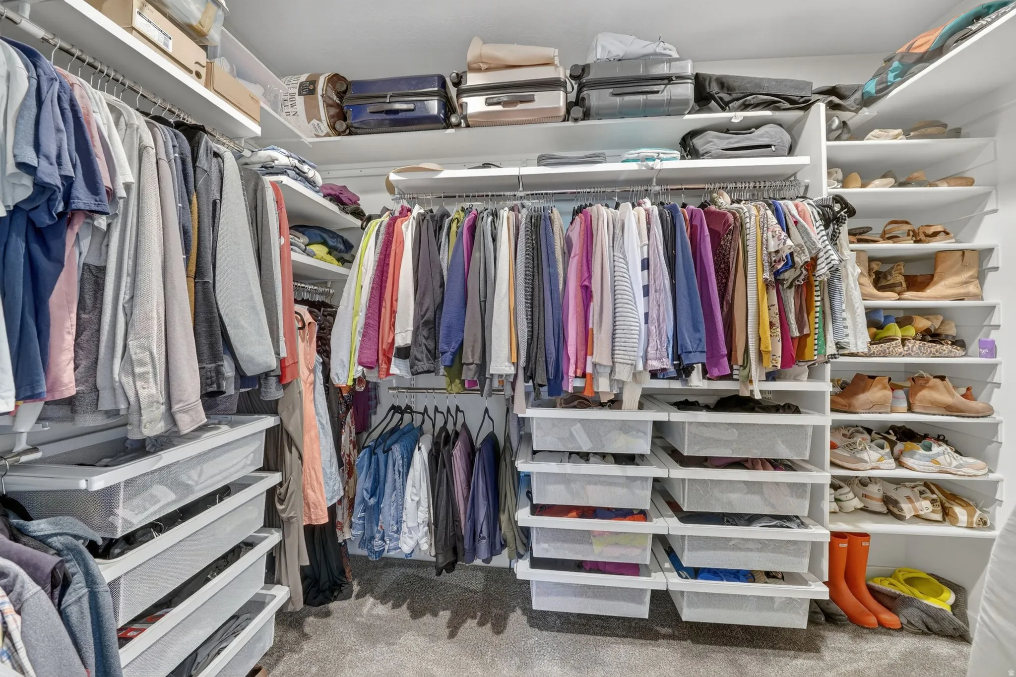 Custom closet system featuring multiple hanging rods, integrated shelving, and pull-out storage bins