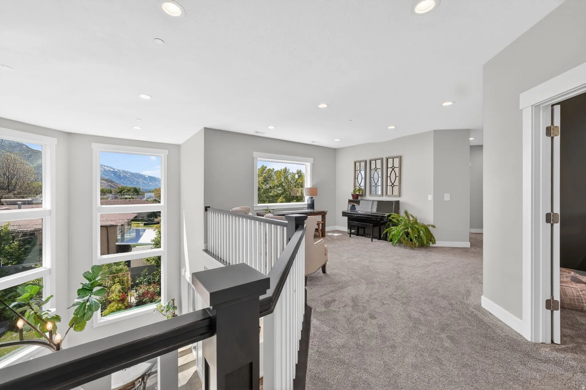 Upper-level landing featuring a carpeted floor, recessed lighting, and a white and dark-toned balustrade