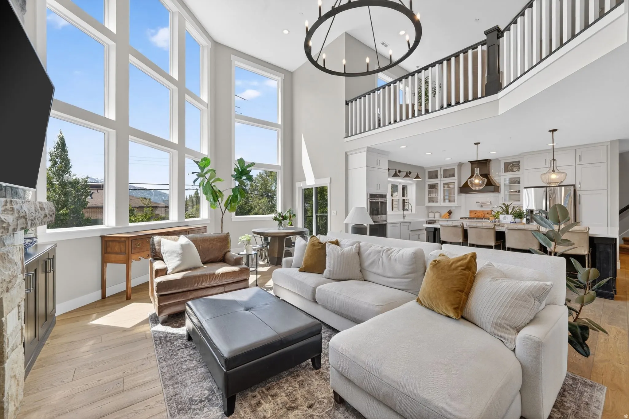 Two-story living area featuring tall window banks, a stone-faced fireplace with built-in cabinetry, and wood-finish flooring