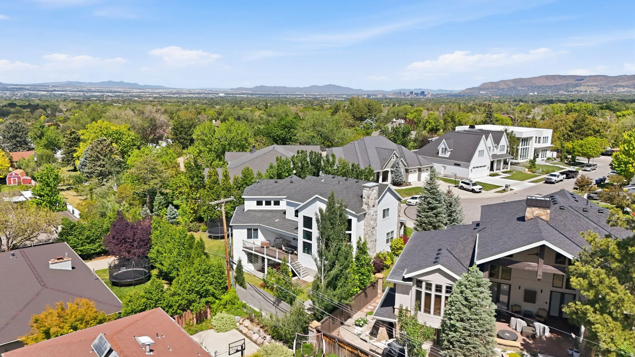 Modern architectural residence featuring a multi-level design, a prominent stone chimney, and a rear balcony