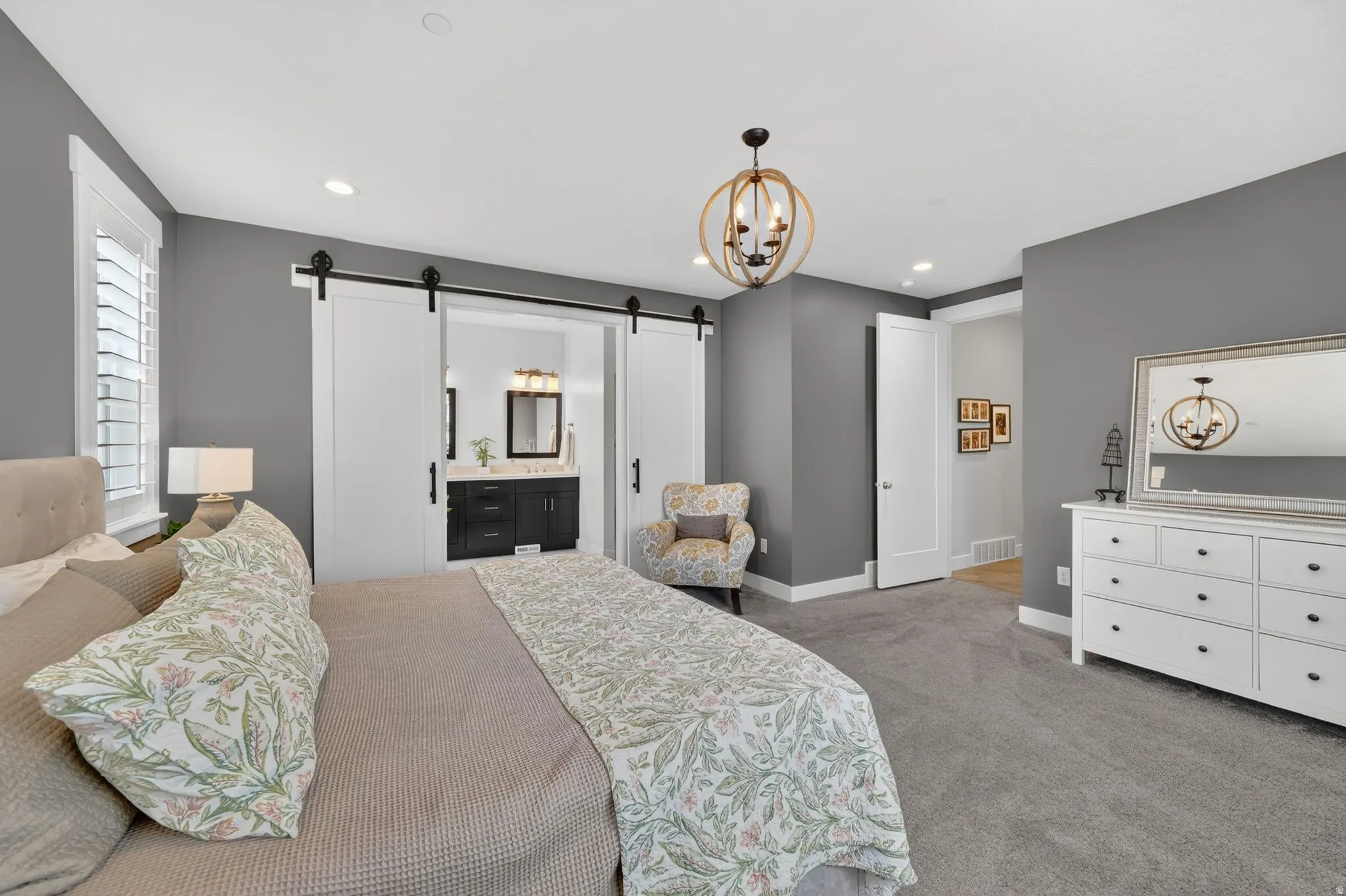 Spacious room featuring gray walls, gray carpeting, a decorative chandelier, and white plantation shutters