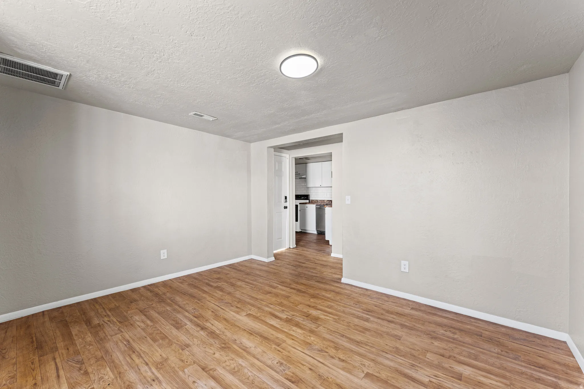 Spacious room featuring wood-finish flooring, light gray walls, and white trim