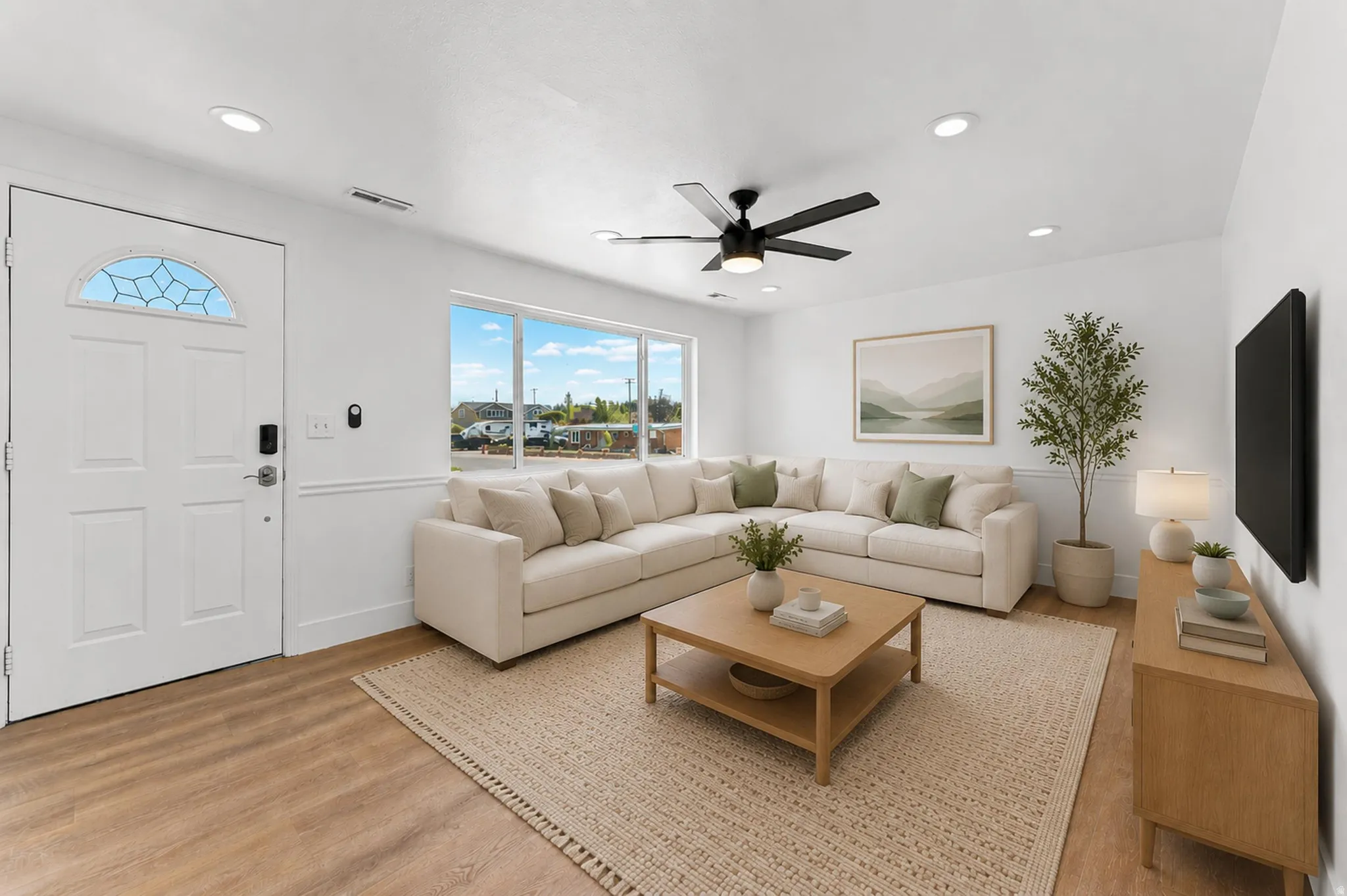 Light-filled living area featuring wood-finish flooring, a contemporary ceiling fan, recessed lighting, expansive windows, and a panel door with an arched decorative glass insert