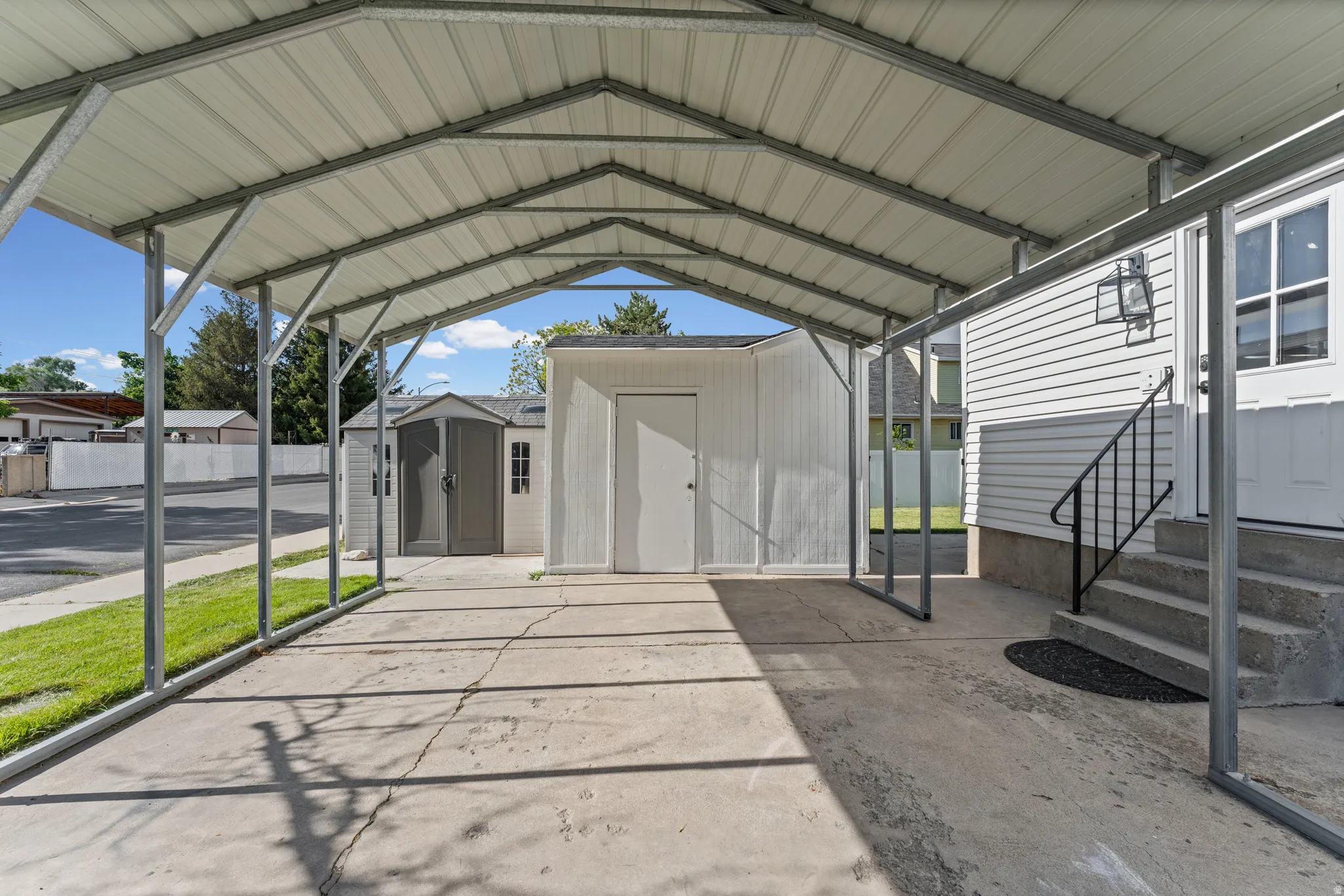 Covered carport with a metal roof and concrete pad, providing sheltered parking