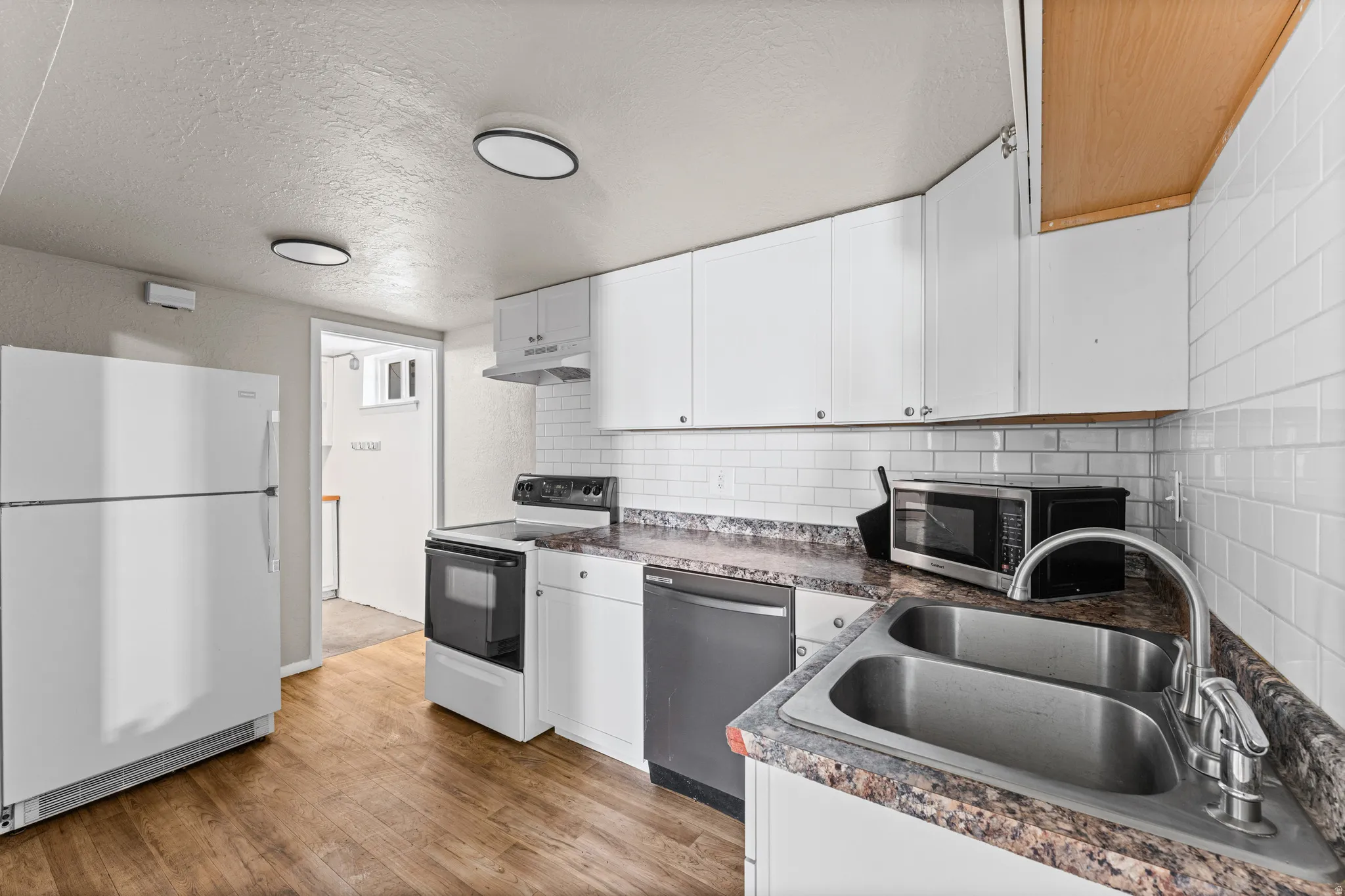 Kitchen featuring wood-finish flooring and white cabinetry
