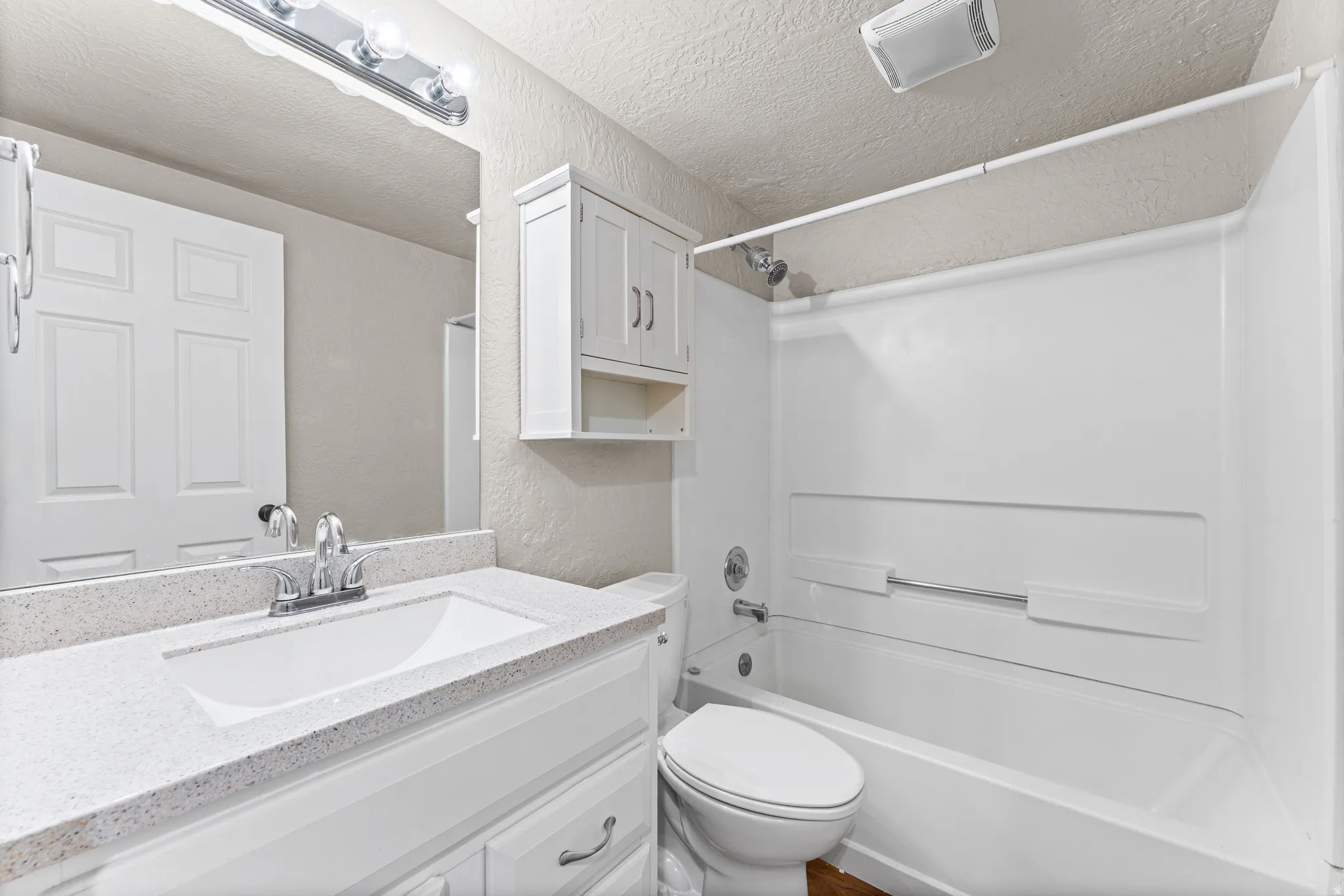 Bathroom featuring a white vanity with a speckled countertop, an integrated sink, a chrome faucet, and a large wall mirror