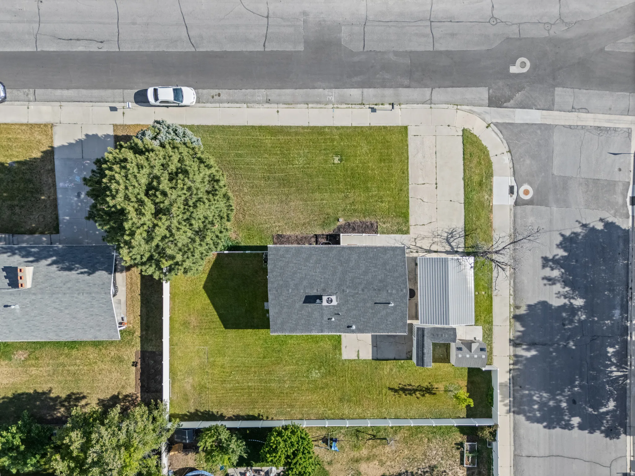 Property featuring a dark shingle roof, mature front yard tree, green lawns, and a concrete driveway
