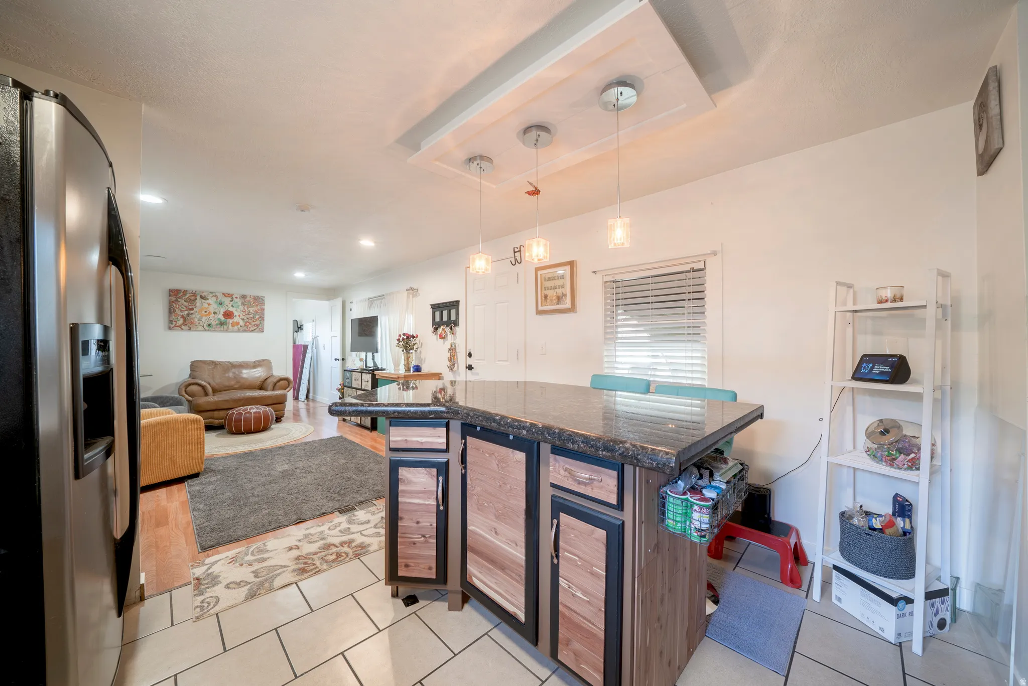 Kitchen island with dark countertop and integrated storage, featuring three pendant lights above