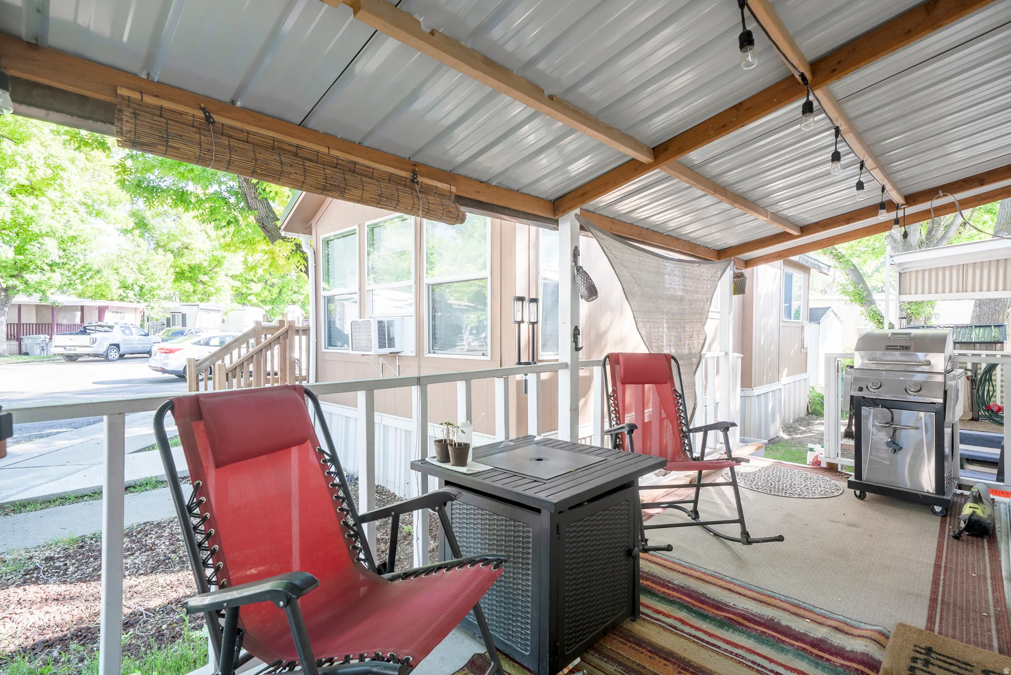 Covered outdoor patio featuring a corrugated metal roof, exposed wood beams, and string lighting