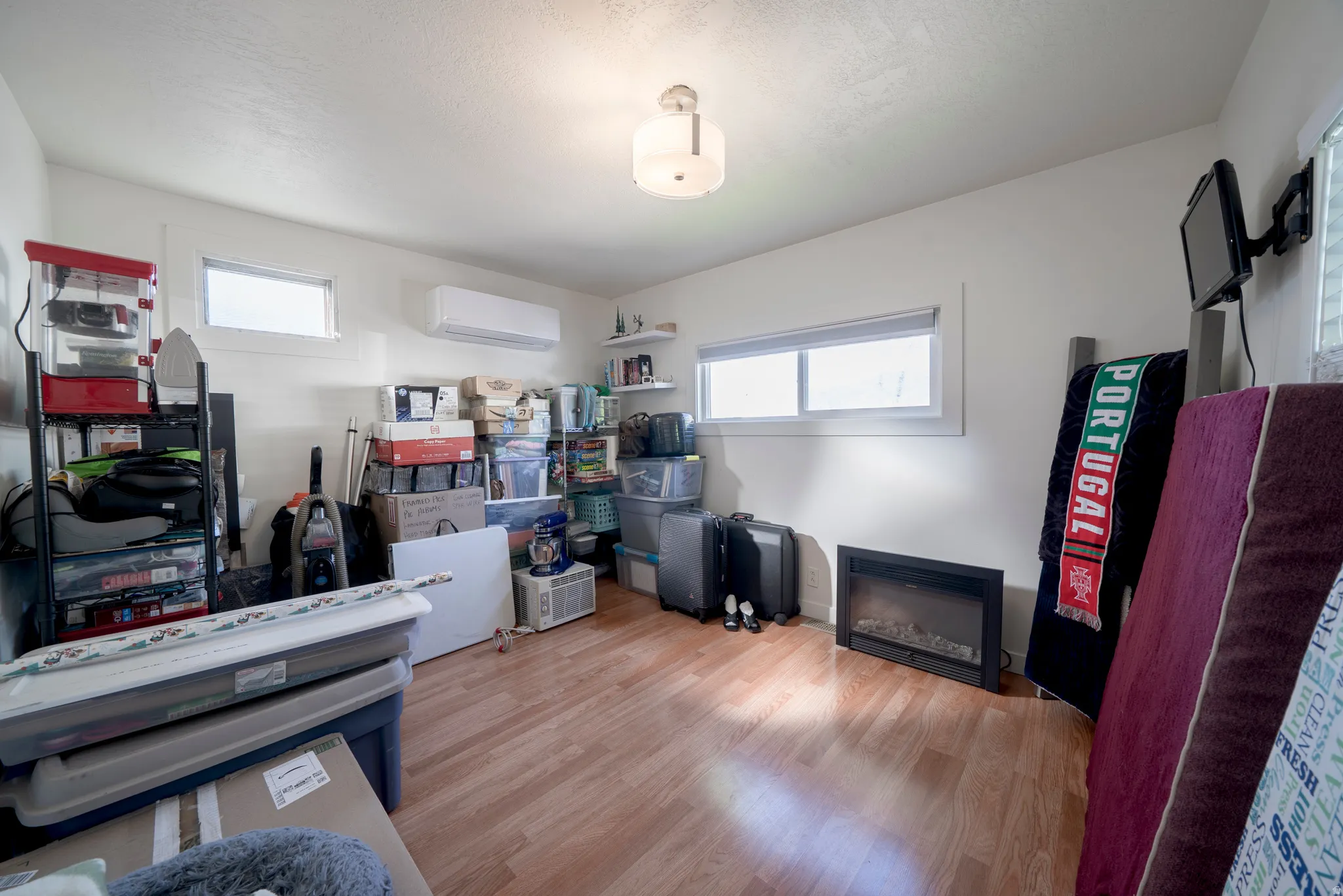 Room featuring wood-finish flooring, white walls, and multiple windows with white blinds