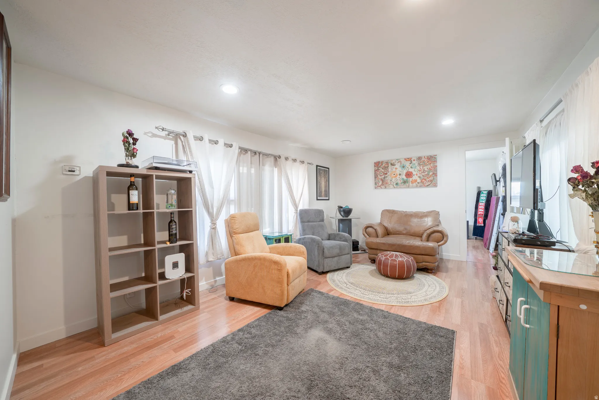 Spacious living area featuring light wood-finish flooring, recessed lighting, and white walls