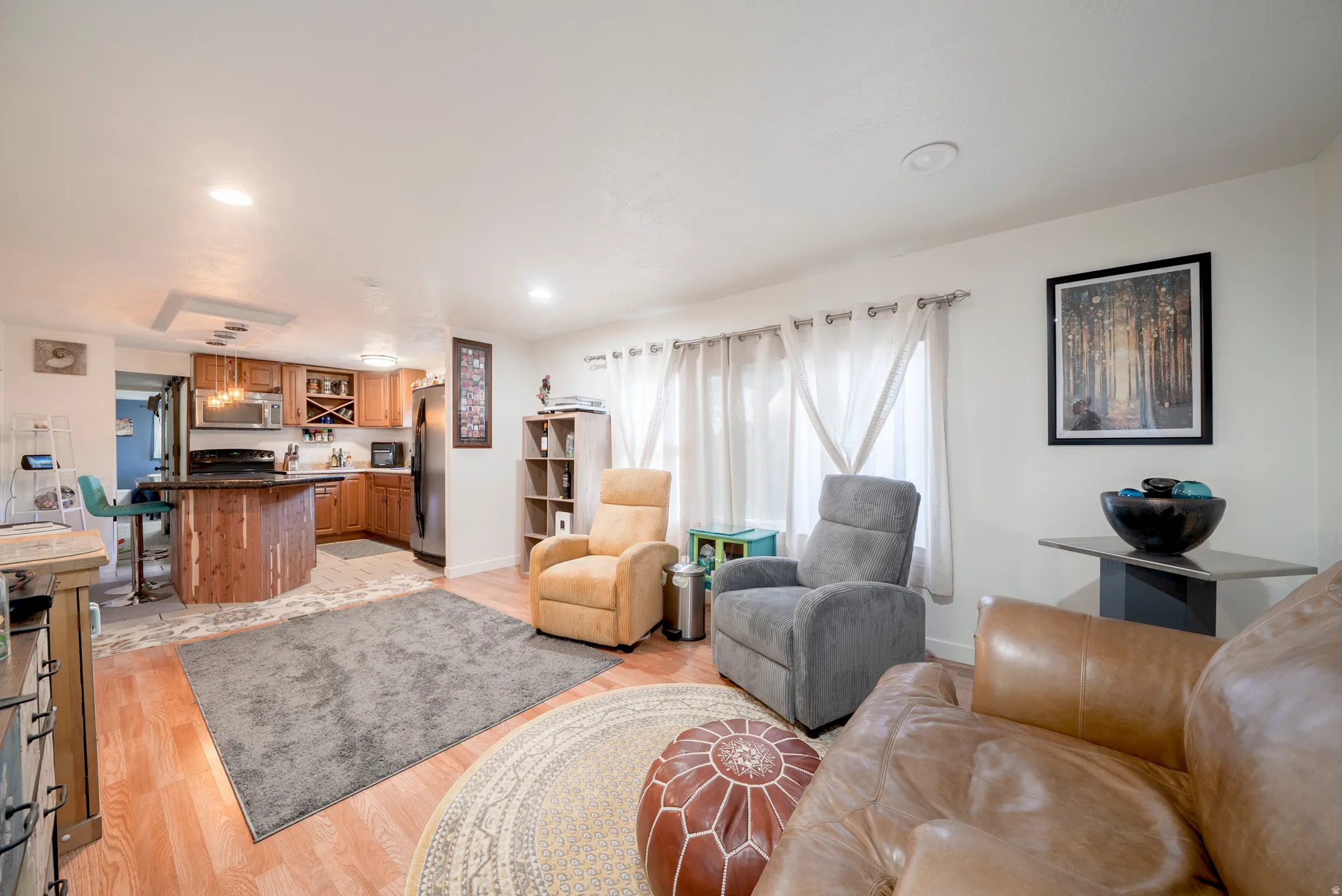 Living area featuring wood-finish flooring, recessed lighting, and a kitchen with wood cabinetry