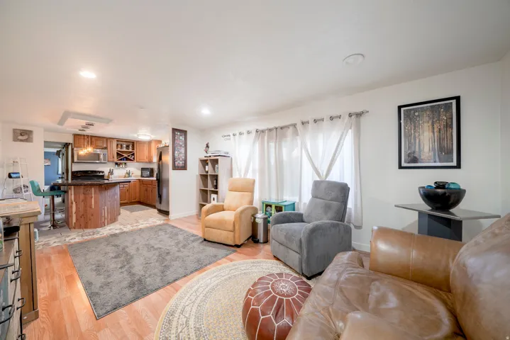 Living area featuring wood-finish flooring, recessed lighting, and a kitchen with wood cabinetry