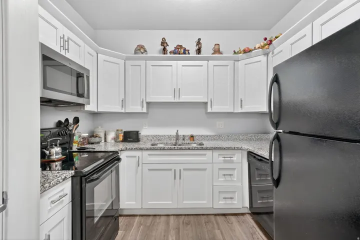 Kitchen featuring white shaker-style cabinetry, light-toned countertops, and wood-finish flooring
