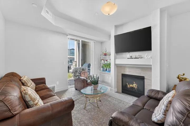 Living area featuring a gas fireplace with a tiled surround and mantel, sliding glass doors, carpet flooring, and a ceiling-mounted light fixture