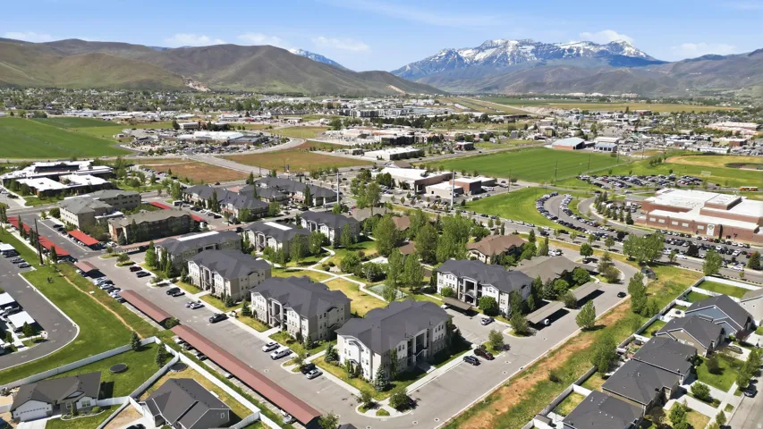 Expansive aerial showcasing a residential community with multi-story buildings, covered parking areas, and green spaces