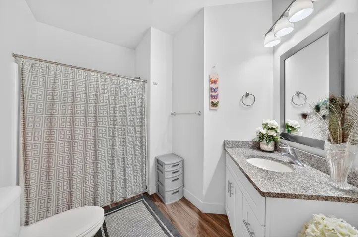 Bathroom featuring a single vanity with granite countertop, undermount sink, and chrome faucet