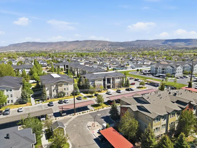 Aerial perspective showcasing a community of multi-story residential buildings with surrounding paved parking areas