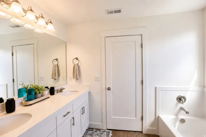 Spacious bathroom with a double vanity featuring white cabinetry, integrated sinks, and brushed nickel hardware