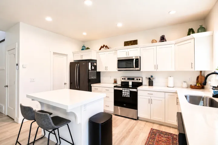 Bright kitchen featuring white shaker cabinetry, stainless steel appliances, a white subway tile backsplash, and a large central island with a solid surface countertop
