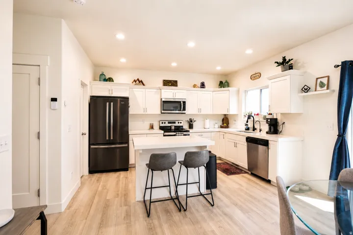 Contemporary kitchen featuring light wood-finish flooring, white cabinetry, recessed lighting, and stainless-steel appliances