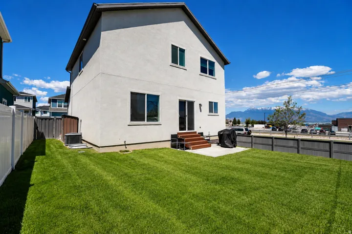 Expansive green lawn with a concrete patio and wood-finish steps