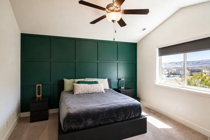 Accent wall with decorative paneling, vaulted ceiling, and ceiling fan with integrated lighting