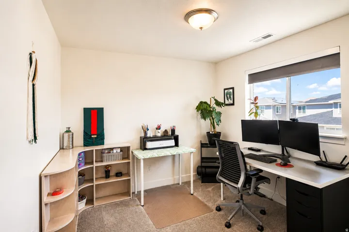 Bright room featuring a large window, neutral wall paint, ceiling-mounted light fixture, and carpet flooring