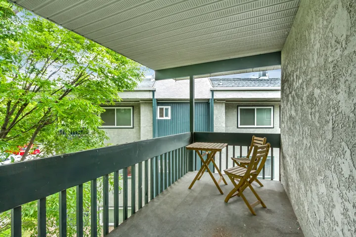 Private balcony featuring a textured exterior wall, a durable concrete floor, and a slatted railing