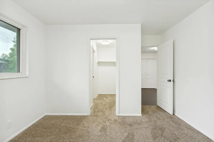 Room featuring neutral carpeting, white walls, and a window with white trim