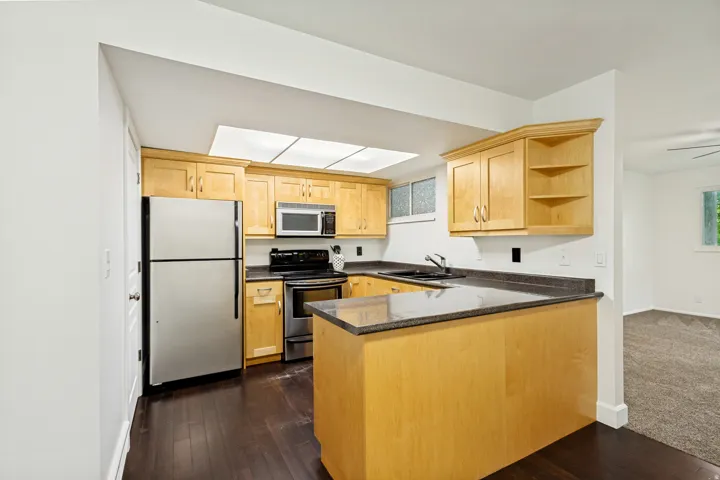 Kitchen featuring wood-finish cabinetry, dark countertops, and stainless steel appliances