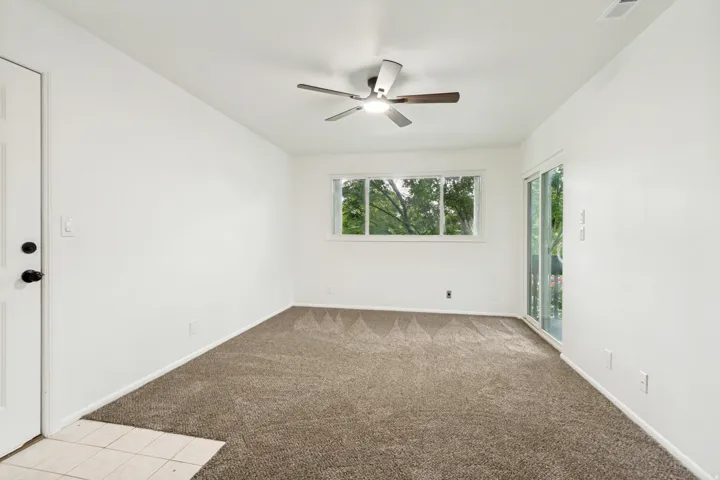 Bright interior space featuring a ceiling fan, carpet flooring, and a large window