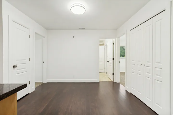 Spacious interior featuring dark wood-finish flooring, white walls, and bright overhead lighting