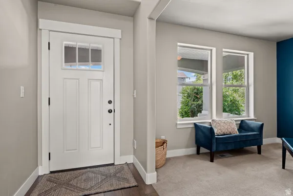 Entryway with a white paneled door featuring upper glass lites, dark hardware, and wide trim