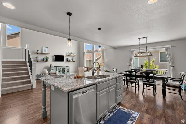 Kitchen island with granite countertop, double basin sink, and stainless steel dishwasher