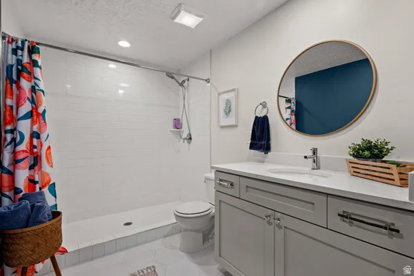Bathroom featuring a single vanity with stone countertop, undermount sink, and chrome faucet