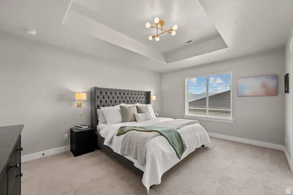 Spacious room featuring a tray ceiling, contemporary ceiling light fixture, and light-colored carpet flooring
